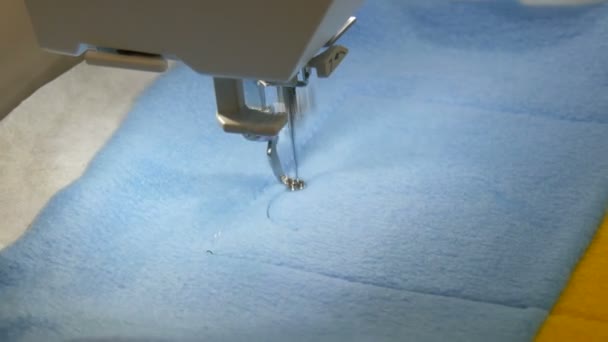 La aguja de la máquina de coser para bordar hace un adorno en un pedazo de tela azul y amarilla. Máquina de coser especial para bordar en el trabajo. Máquina de coser programable — Vídeo de stock
