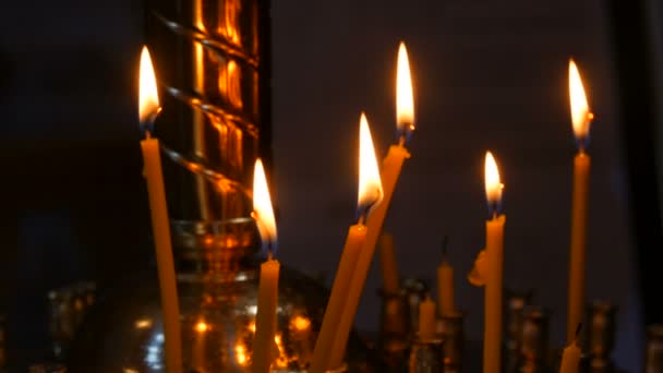 Długie cienkie świece woskowe płoną płomieniem w cerkwi prawosławnej, rytuały pamiątkowe dla chrześcijan — Wideo stockowe