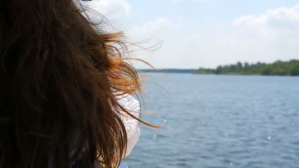 Красиве довге темне волосся молодої дівчини пливе на тлі подорожі на човні влітку, блакитна прозора вода блищить і відображає сонячне світло. Розслабтеся концепція, відпочиньте — стокове відео