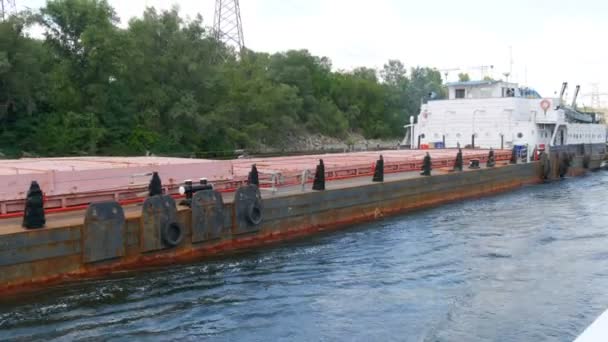 Zaporozhye, Ουκρανία - 19 Ιουνίου 2020: Το πλοίο πλέει πέρα από ένα μεγάλο παλιό σκουριασμένο φορτηγίδα, στον ποταμό Δνείπερου, η επιγραφή του ονόματος πλοίων στα ρωσικά — Αρχείο Βίντεο