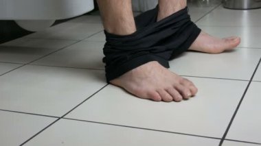 Banyoda tuvalette oturan bir adamın bacakları. Dışkılama işlemi. Evdeki tuvalet. Sabahları sağlıklı bağırsak hareketleri.