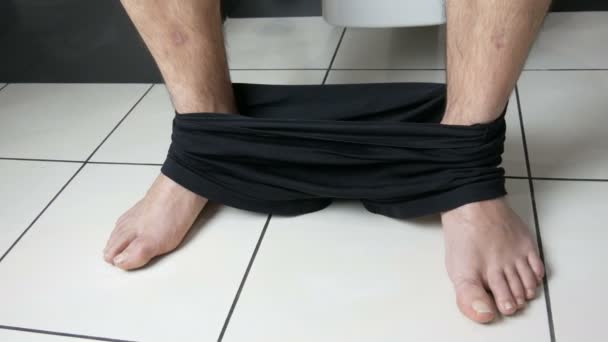 Picioarele unui bărbat care stă pe toaleta din baie. Procesul de defecare. Toaleta acasă. Mișcări intestinale sănătoase dimineața — Videoclip de stoc