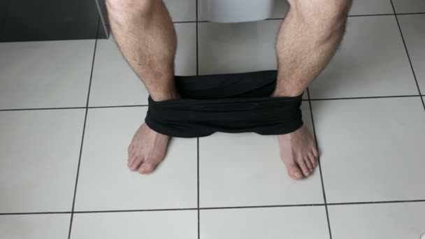 Legs of a man sitting on the toilet in the bathroom. Defecation process. Toilet at home. Healthy bowel movements in the morning — Stock Video