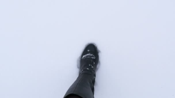 Draufsicht auf Frauenbeine in hohen schwarzen Lederstiefeln Spaziergang im Winterschnee pov Video Detailansicht — Stockvideo