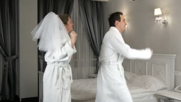 23. ledna 2021 - Kamenskoe, Ukrajina: Vtipný novomanželský pár vesele tančí v hotelu. Nevěsta v závoji a bílý župan s ženichem baví a radují — Stock video