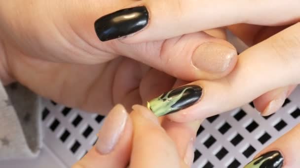 A manikűrös festeni egy hosszú, meghosszabbított köröm egy ügyfél fekete és világos zöld körömlakk — Stock videók