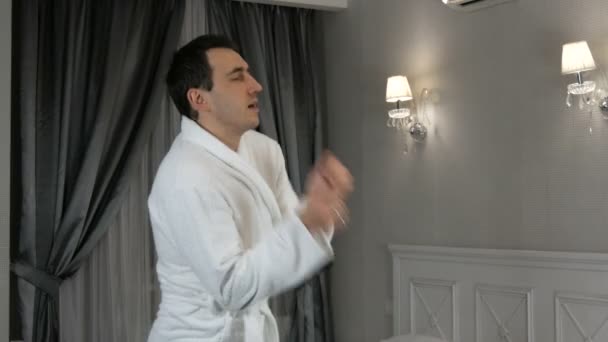 23 janvier 2021 - Kamenskoe, Ukraine : Un jeune bel homme en peignoir blanc s'amuse et danse dans une chambre d'hôtel — Video