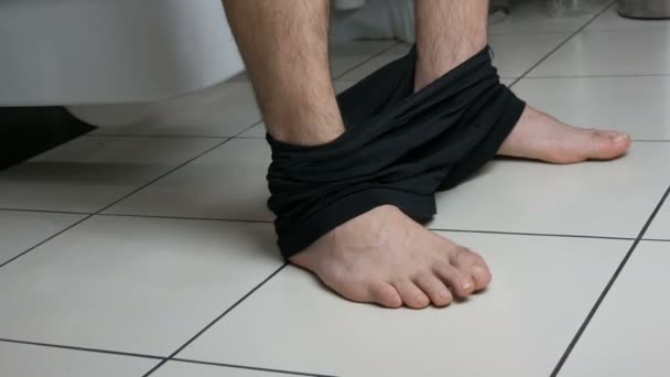 Gambe di un uomo seduto sul water in bagno. Processo di defecazione. Servizi igienici a casa. Movimenti intestinali sani al mattino — Video Stock