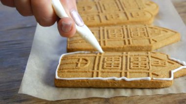 Kahverengi zencefilli kek kreması. Kadın şeflerin elleri, ev mutfağında zencefilli kek yapan bir evde beyaz şeker kreması ve pasta poşeti ile süslenir. Yeni yıl gelenekleri