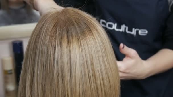20. Januar 2021 - Kamenskoe, Ukraine: Die weiblichen Hände des Friseurs schneiden den Mädchen die Enden der Haare. Lange, gesunde, glänzend dicke Haare einer jungen Frau von blonder Farbe — Stockvideo