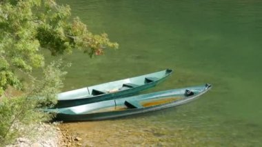 Turkuazın arka planında iki boş zevk ya da balıkçı teknesi bir tatlı su nehri ya da gölün şeffaf suları.