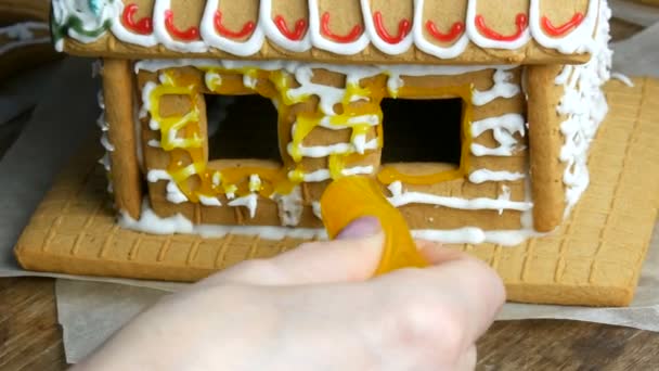 Gelado de gengibre. Chefs mãos femininas decorar com açúcar amarelo cereja e pastelaria com um saco de casa de gengibre na cozinha da casa. Tradições de Ano Novo — Vídeo de Stock