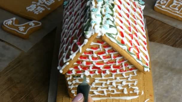 Gingerbread frosting. Chefs female hands decorate with green sugar icing and pastry shop with a bag of gingerbread house in the home kitchen. New year traditions — Stock Video