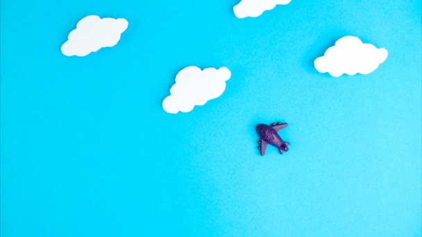 Detener la animación en movimiento. Avioncito azul volando sobre el fondo de nubes cielo azul. Avión, viajes, transporte aéreo, bloqueo final y concepto de cuarentena — Vídeo de stock