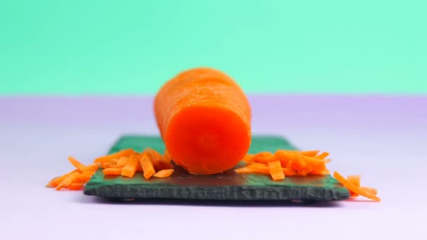 Animasi gerakan berhenti, wortel oranye besar dipotong dan disusun kembali. Kartun konsep makanan vegetarian yang sehat. Memotong wortel dekat papan tulis hitam batu — Stok Video