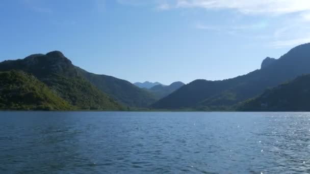 Fiume blu che scorre attraverso la valle verde verso montagne lontane. curve e curve del fiume Crnojevica nel parco nazionale del Montenegro, serpeggiando attraverso la palude tra le colline sulla strada per il lago Skadar — Video Stock
