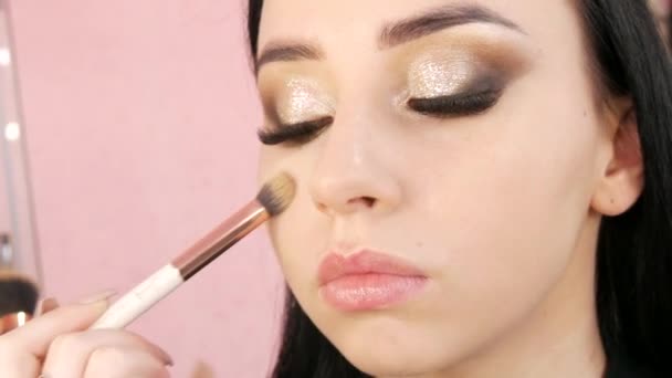 Estilista de maquillaje aplica la base en la cara de los modelos con un cepillo especial — Vídeos de Stock