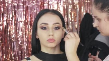 Profesyonel makyaj ustası, özel bir fırça kullanarak modellerin yüzüne temel atar.