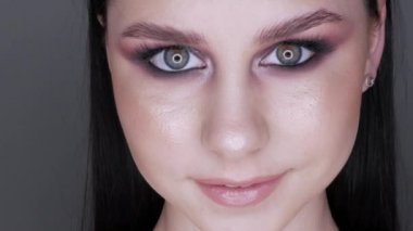 Şık makyajlı, dumanlı, poz veren ve gülümseyen güzel genç kız modeli.