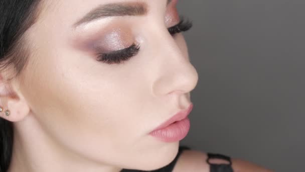 Hermosa joven modelo posando en el estudio con noche elegante maquillaje ojos ahumados. Cabello largo negro y ojos marrones — Vídeos de Stock