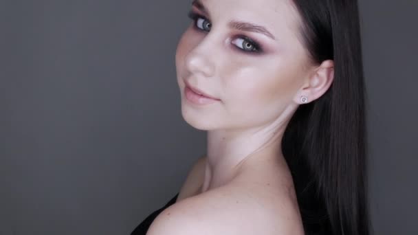 Schöne junge Mädchen Modell mit stilvollem Abend Make-up rauchige Augen posieren und lächeln, High Fashion auf grauem Hintergrund — Stockvideo