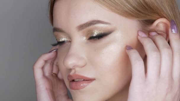 Portrait of a beautiful young girl model in stylish evening make up smoky eyes with beautiful golden eyeshadow and delicate lipstick on the lips. Eyes close up view — Stock Video