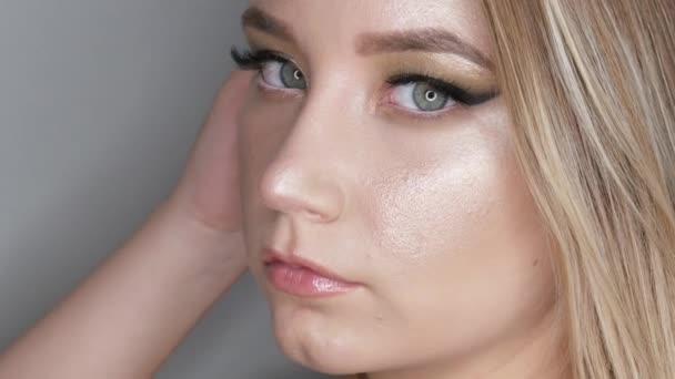 Retrato de una hermosa joven modelo en elegante noche maquillaje ojos ahumados mira a la cámara y posando cara vista de cerca — Vídeos de Stock