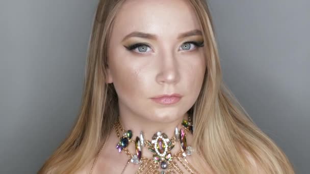 Портрет красивой молодой девушки модели в стильный вечер составляют дымчатые глаза смотрит на камеру и позирует с красивым ожерельем в камнях — стоковое видео