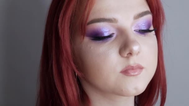Vista de cerca de hermosa modelo de chica joven con el pelo rojo brillante y maquillaje púrpura posando en el estudio — Vídeos de Stock