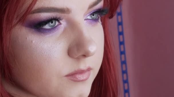 Close-up view of beautiful young girl model with bright red hair and purple makeup posing in the studio — Stock Video