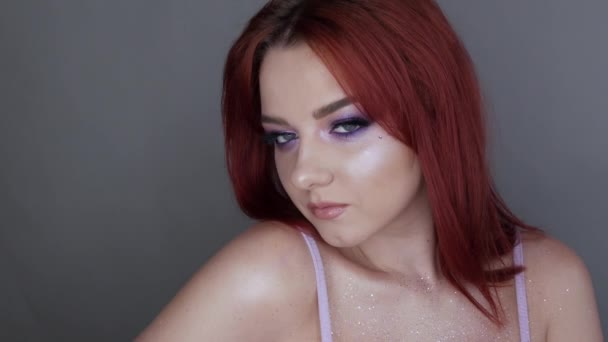 Közelkép a gyönyörű fiatal lány modell élénk vörös haj és lila smink pózol a stúdióban — Stock videók