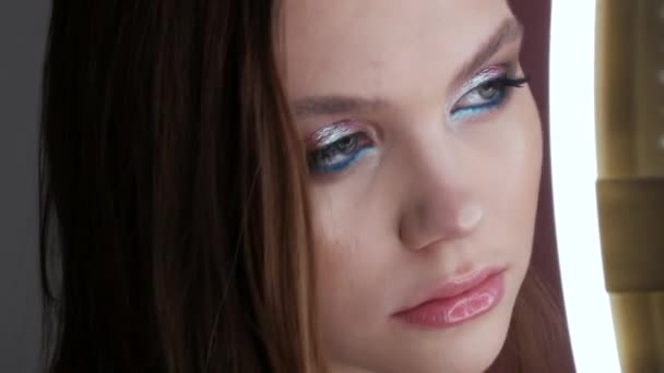 Portrait of a beautiful young girl model in stylish evening make up smoky eyes posing. Eyes close up view. Long eyelash extensions and eye makeup in delicate turquoise tones and transparent lip gloss — Stock Video