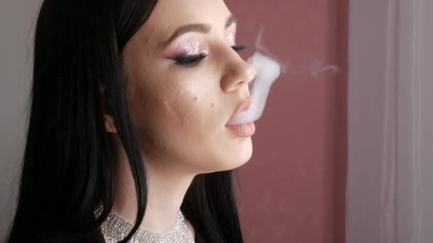 Belle et jeune fille modèle souffle de la fumée de sa bouche à l'aide d'une cigarette électronique. Problème Mauvaises habitudes et dépendance au tabagisme. Moderne élégant soir lumineux maquillage yeux fumés — Video