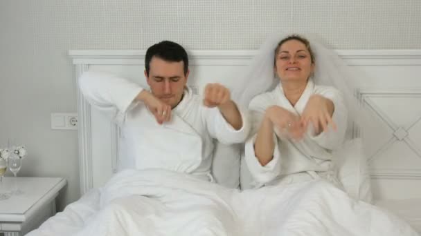 2021年1月23日-ウクライナ、カマンスコエ:ベッドで陽気に踊るホテルで新婚カップルと面白い結婚。ベールに花嫁と楽しさと喜びを持って新郎と白いバスローブ — ストック動画