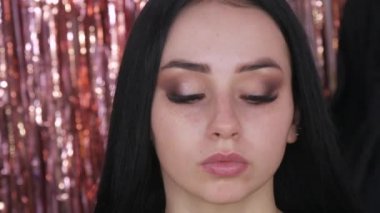 Parlak bir makyajla aşağıya bakan güzel, genç bir kız.