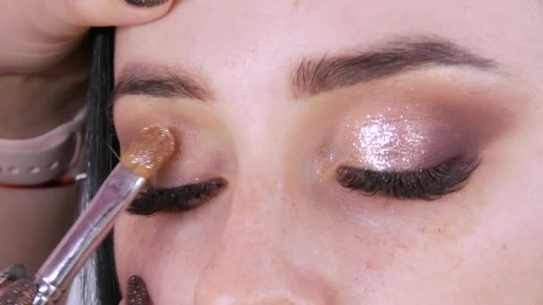 Jasné večerní make-up, který make-up umělec dělá pro mladý model se speciálním štětcem aplikuje stíny a oční linky — Stock video