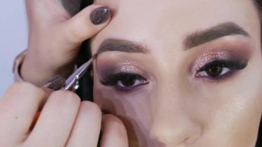 Fırça, kaşlara gölge sürerek güzel, genç bir modelin şeklini düzeltir. Smoky eyes için akşam makyajı için.