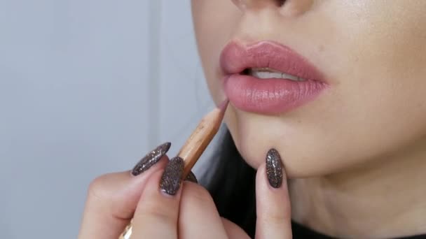 Een speciale borstel brengt mooie lippenstift aan op de lippen van een jong model meisje met een stijlvolle, heldere avondmake-up close-up — Stockvideo