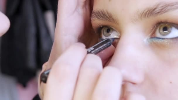 Stylist make-up master maakt een oogje op de avond stijlvolle heldere make-up op een jong meisje model in een beauty studio — Stockvideo