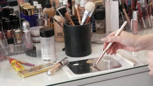 22 mars 2021 - Kamenskoe, Ukraina: Professionella makeupartister bord med många speciella borstar, ögonskuggspaletter, läppstift. Brush plockar upp grunden för ytterligare applicering av ansiktsmakeup — Stockvideo