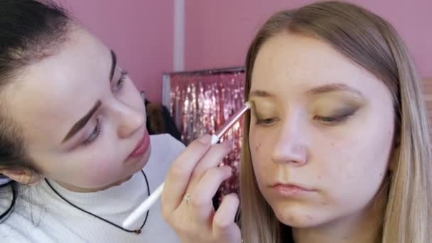 Художник-макіяж робить макіяж очей моделі за допомогою спеціальної щітки — стокове відео
