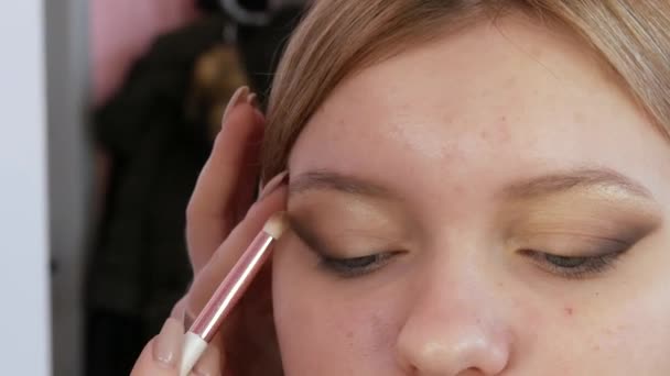 De belles ombres beiges sont appliquées aux yeux du modèle dans le salon de beauté — Video