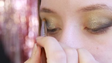 Güzeller güzeli altın rengi gölgeler güzellik salonundaki modelin gözlerine uygulanır.