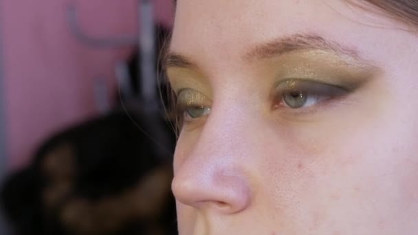 Mooie gouden losse schaduwen worden toegepast op de ogen van het model in de schoonheidssalon — Stockvideo