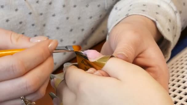 Na gwóźdź nakłada się specjalną akrylową fakturę i koryguje kształt gwoździa na specjalnym szablonie. Usługa przedłużania paznokci. Manikiurzystka robi manicure Gel Nail rozszerzenie widok z bliska — Wideo stockowe