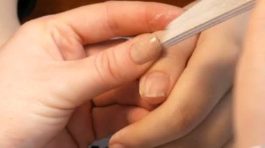Manikürcü tırnakların şeklini özel bir tırnak törpüsüyle dosyalar. Özel manikür araçları ev görüntüsünde tırnakları parlatır