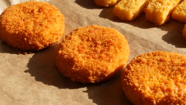 Camembert cheese in batter on a porch with a baking sheet next to fish sticks in batter. Fast food preparation — Stock Video