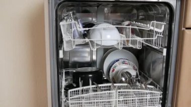 Yıkandıktan sonra açık bir bulaşık makinesinde temiz bulaşıklar. Bir sürü çatal, çatal, kaşık, tabak, tava, temiz ve parlak