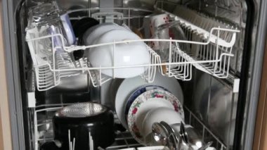 Yıkandıktan sonra açık bir bulaşık makinesinde temiz bulaşıklar. Bir sürü çatal, çatal, kaşık, tabak, tava, temiz ve parlak