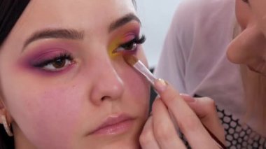 Profesyonel bir makyöz sarı göz farını makyaj stüdyosunda özel bir fırçayla kullanır.
